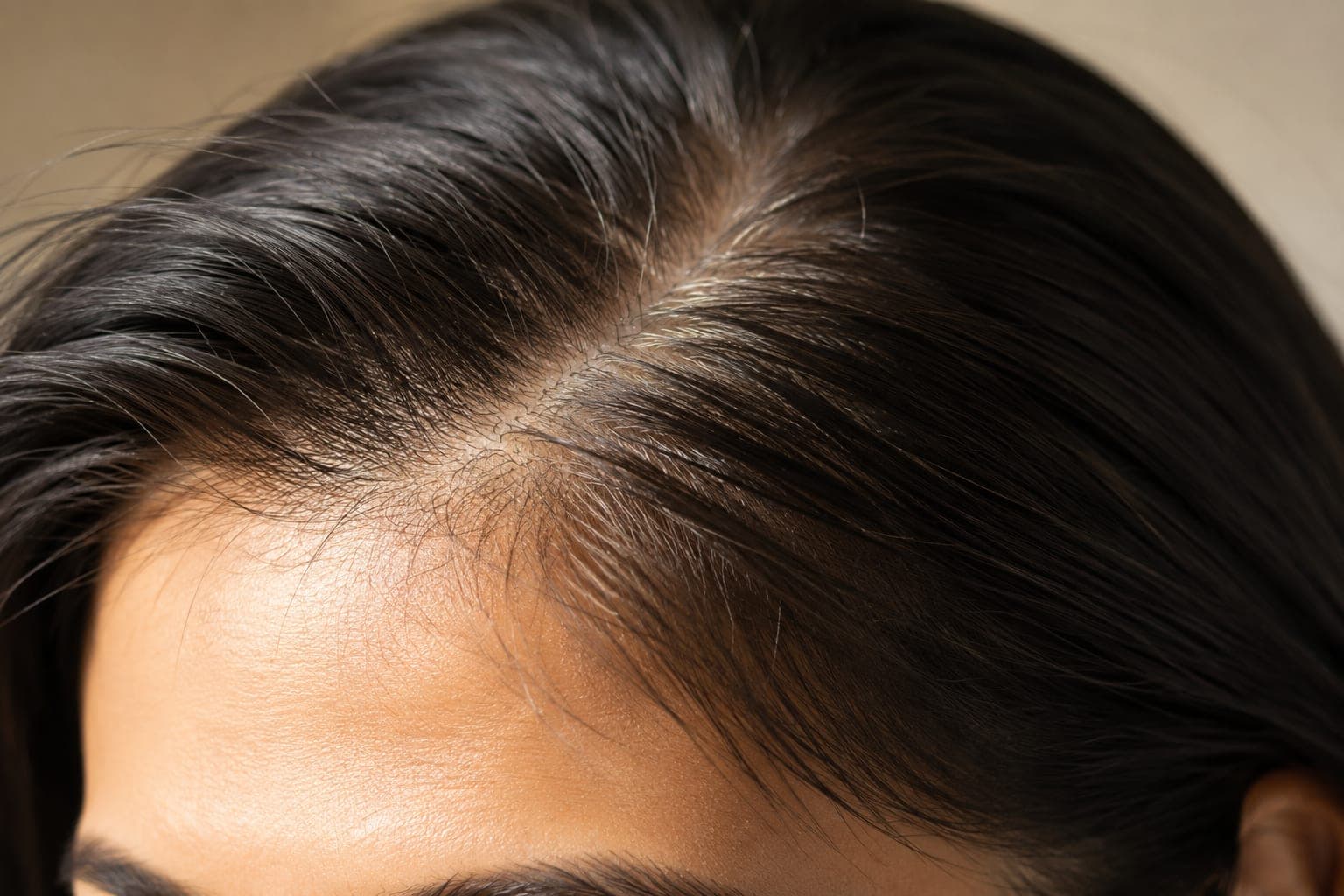 Close-up of a woman's hairline in warm natural light showing fine hair density, editorial quality, science-forward framing